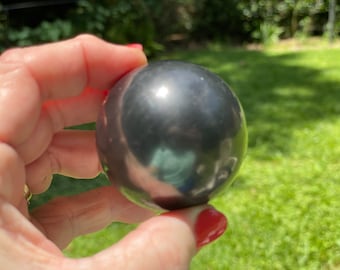 May include: A smooth, black, polished sphere, reflecting light.