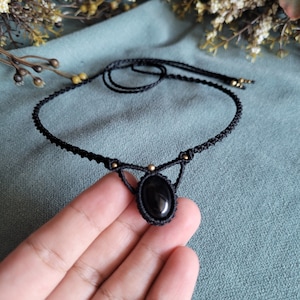 May include: Black choker necklace with a black oval gemstone pendant and gold accents.