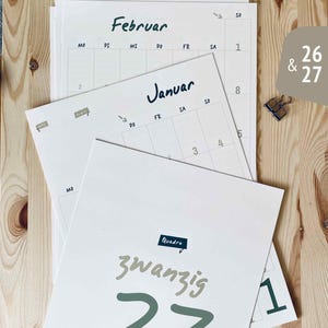 Pode incluir: Um conjunto de p&aacute;ginas de calend&aacute;rio impressas com os meses de Januar e Februar com texto em alem&atilde;o. A folha superior exibe o ano 27 em fonte verde grande com a palavra zwanzig acima. As p&aacute;ginas incluem layouts de grade para os dias.