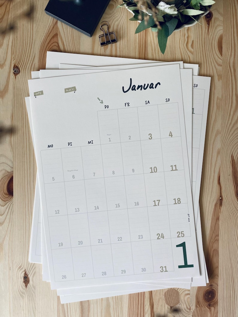 Pode incluir: Uma p&aacute;gina de calend&aacute;rio mensal em papel branco para janeiro com texto e linhas de grade em preto. O calend&aacute;rio apresenta os dias da semana rotulados MO, DI, MI, DO, FR, SA, SO e datas numeradas de 1 a 31. Um grande n&uacute;mero 1 verde est&aacute; impresso no canto inferior direito.