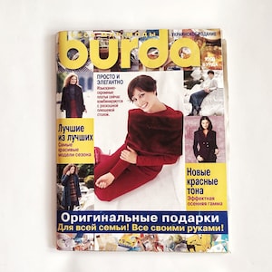 May include: A magazine cover for Burda, a Ukrainian edition of a fashion magazine. The cover features a woman wearing a red dress and the text "Original gifts for the whole family! All with your own hands!"