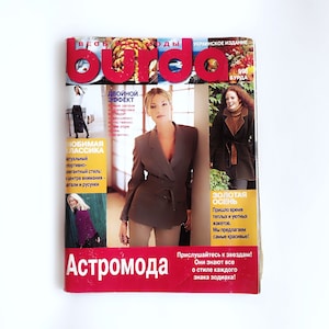 Puede incluir: Una portada de revista para Burda, una revista de moda, con una mujer que lleva un blazer marrón y pantalones caqui. El texto de la portada dice "Burda", "Doble Efecto", "Clásico Favorito", "Otoño Dorado", y "Astro Moda".