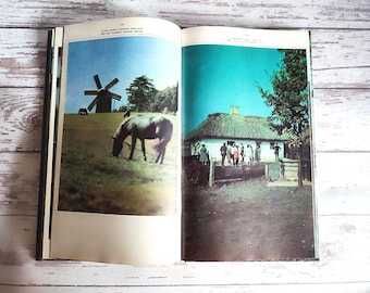 May include: Open book with two images. One shows a windmill on a grassy hill with a horse grazing. The other depicts a white building with a thatched roof and people standing outside. The sky is blue in both images.