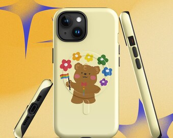 Puede incluir: Una funda de teléfono de color amarillo pálido con la ilustración de un oso marrón que sostiene una bandera arcoíris, rodeado por un arreglo circular de flores coloridas. El oso lleva una pajarita roja y un botón multicolor.