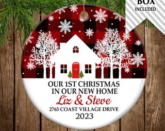 May include: Red and black buffalo plaid Christmas ornament with a white silhouette of a house, trees, and snowflakes. The ornament reads "Our 1st Christmas in our new home Liz & Steve 2763 Coast Village Drive 2023".