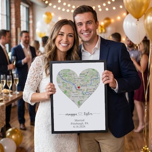 May include: A rectangular framed print featuring a heart-shaped map of Pittsburgh, Pennsylvania, with a red heart icon. Below the map, the text reads "maggie & tyler", "Married", "Pittsburgh, PA", and the date "4.18.2026" in black lettering.