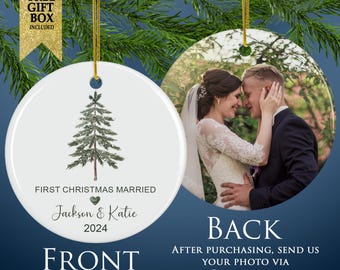 May include: A round white ceramic ornament featuring a green pine tree illustration, the text FIRST CHRISTMAS MARRIED, a small green heart, the names Jackson & Katie, and the year 2024. The reverse side displays a photograph of a couple.
