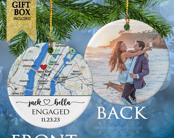 May include: A white ceramic ornament with a map of New York City on the front and the text "jack bella ENGAGED 11.23.23". The back of the ornament features a photo of a couple on a beach.