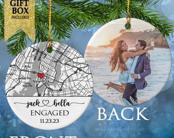 May include: A white ceramic Christmas ornament with a map of New York City on the front. The map includes the text "jack bella ENGAGED 11.23.23". The back of the ornament has a photo of a couple.