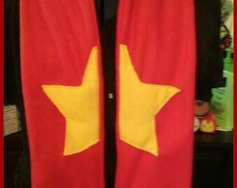 May include: Red fleece scarf with a yellow star in the center. The scarf has blue fringe at the bottom and the text "@nairawr" is written on the scarf.