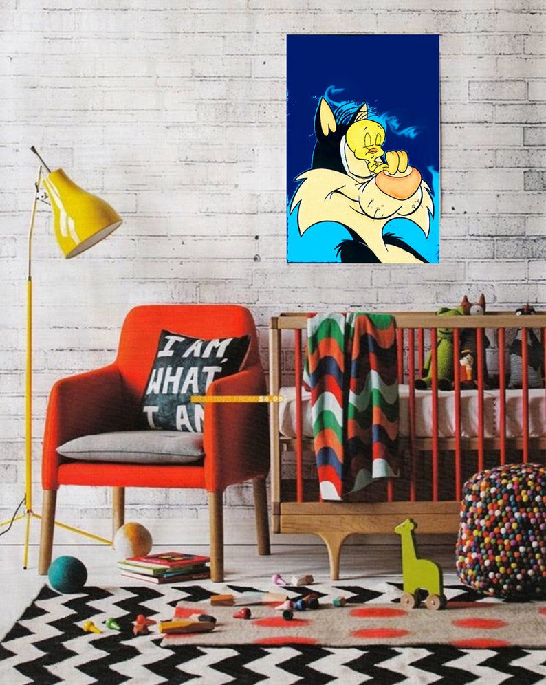 May include: A cartoon illustration of Sylvester the Cat and Tweety Bird. Sylvester is a large, black cat with a blue background. Tweety Bird is a small, yellow bird with a black outline. Sylvester is holding Tweety Bird in his mouth. The illustration is printed on a canvas and framed. The canvas is hanging on a white brick wall. There is a red armchair with a pillow that says 'I am what I am' in black text. There is a crib with a colorful blanket and a green giraffe toy. There is a multi-colored beanbag chair in the foreground.