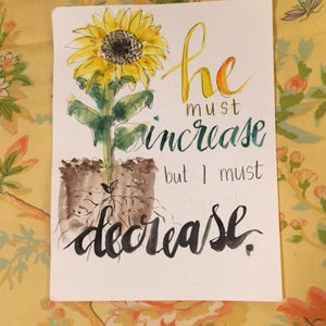 May include: Watercolor painting of a sunflower with the text "he must increase but I must decrease."