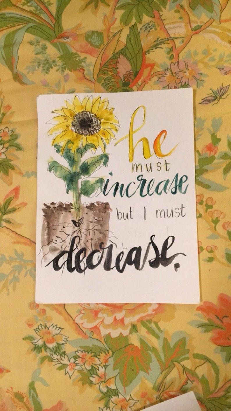 May include: Watercolor painting of a sunflower with the text "he must increase but I must decrease."