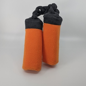 May include: Two orange and black dog chew toys made of fleece. The toys are connected by a black rope.