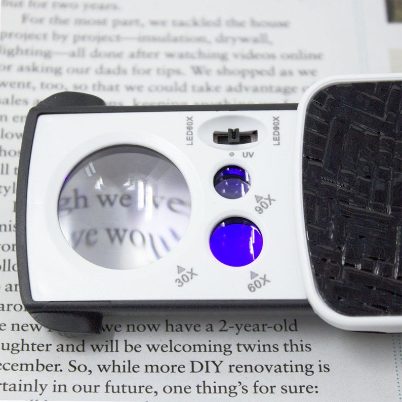 May include: A white and black handheld magnifying glass with a built-in UV light. The magnifying glass has a lens with a 30x, 60x, and 90x magnification. The text "LED90X" and "LED60X" is printed on the side of the magnifying glass.