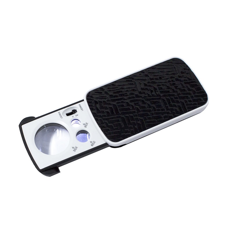 May include: A white and black magnifying glass with a black leather-like case. The magnifying glass has a built-in LED light and multiple magnification levels: 3X, 6X, 8X, and 12X.