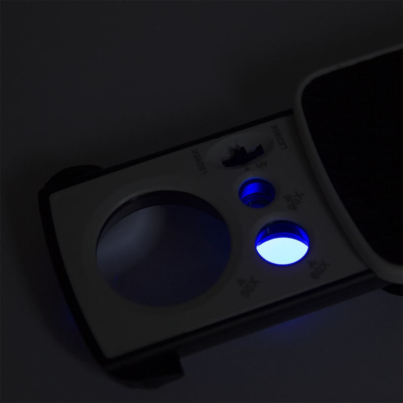 May include: A white and black handheld magnifying glass with a blue LED light. The magnifying glass has a round lens and a handle with buttons labeled "LED", "UV", "30X", "60X", and "100X".