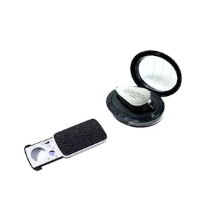 May include: A black and silver magnifying glass with a built-in LED light. The magnifying glass is in a black case with a mirror lid. The magnifying glass has a 60mm lens and is ideal for viewing small objects.