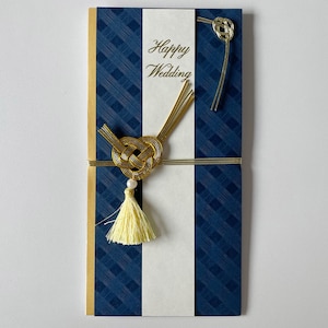 May include: A wedding card with a navy blue and white design, featuring the text "Happy Wedding" in gold. The card is adorned with gold accents, a decorative knot, and a yellow tassel.