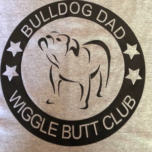 May include: Black and white graphic design of a bulldog with the text "Bulldog Dad Wiggle Butt Club" in a circle with five stars.