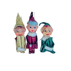 May include: Three vintage Christmas elf ornaments with felt hats and faces. The elves are wearing gold, red, and green outfits with glitter accents.