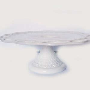 K&ouml;nnte beinhalten: Wei&szlig;er Milchglas-Kuchenst&auml;nder mit gewelltem Rand und einem Sockel mit Diamantenmuster.