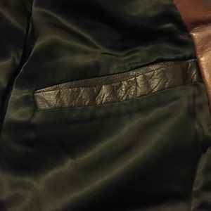 Op de afbeelding: Close-up van de binnenkant van een bruin leren jack, met een zwarte satijnen voering en een leren zak.