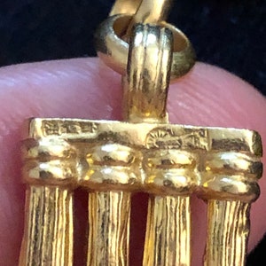 Puede incluir: Encanto de colgante dorado con un dise&ntilde;o de cuatro columnas verticales. El encanto tiene un bucle en la parte superior para sujetarlo a un collar o pulsera.
