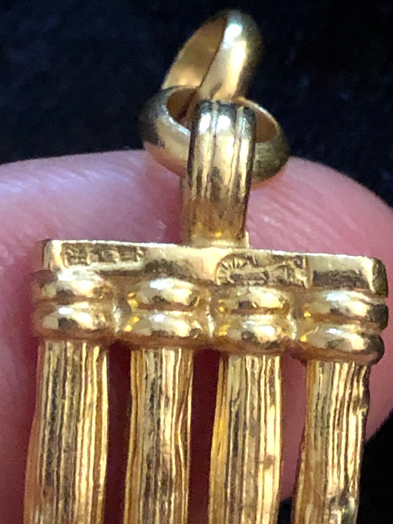 Puede incluir: Encanto de colgante dorado con un dise&ntilde;o de cuatro columnas verticales. El encanto tiene un bucle en la parte superior para sujetarlo a un collar o pulsera.