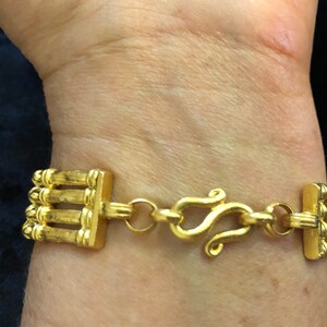 Puede incluir: Un brazalete dorado con un dise&ntilde;o de cadena de m&uacute;ltiples hebras y un cierre de langosta.