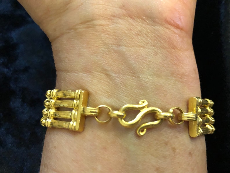 Puede incluir: Un brazalete dorado con un dise&ntilde;o de cadena de m&uacute;ltiples hebras y un cierre de langosta.