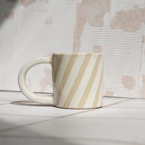 Taza de espresso de gres hecha a mano con rayas y esmaltado rosa y transparente sobre arcilla moteada