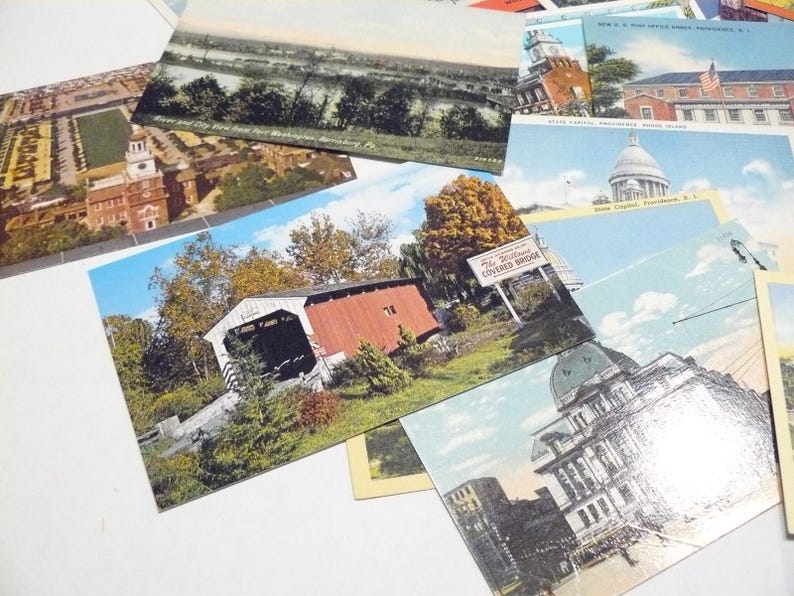 May include: A collection of vintage postcards featuring various scenic views and landmarks. The postcards showcase images of bridges, buildings, and landscapes, with a focus on architectural and natural elements. The postcards are arranged on a white surface.