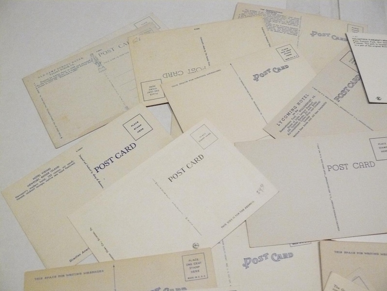 May include: A collection of vintage postcards, with the words "POST CARD" printed on the back. The postcards are cream-colored and arranged in a slightly overlapping pattern. Some have text and stamp boxes.