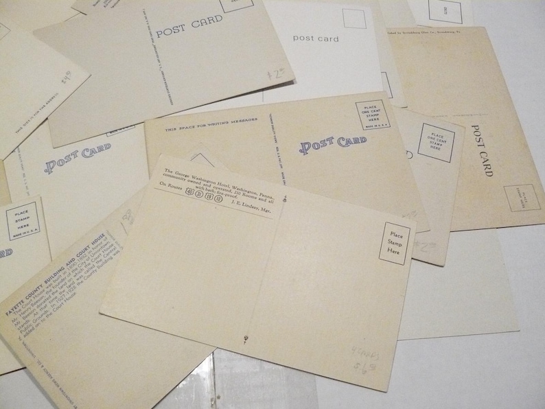 May include: A collection of vintage postcards, with the words "POST CARD" printed in blue. Some cards have text about locations and places for stamps. The cards are beige and arranged on a white surface.