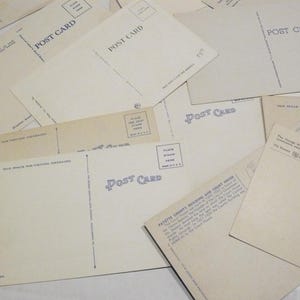 May include: A collection of vintage postcards, with the words "POST CARD" printed on the back. The postcards are cream-colored and feature space for writing messages and placing stamps. Some postcards have text describing buildings and locations.