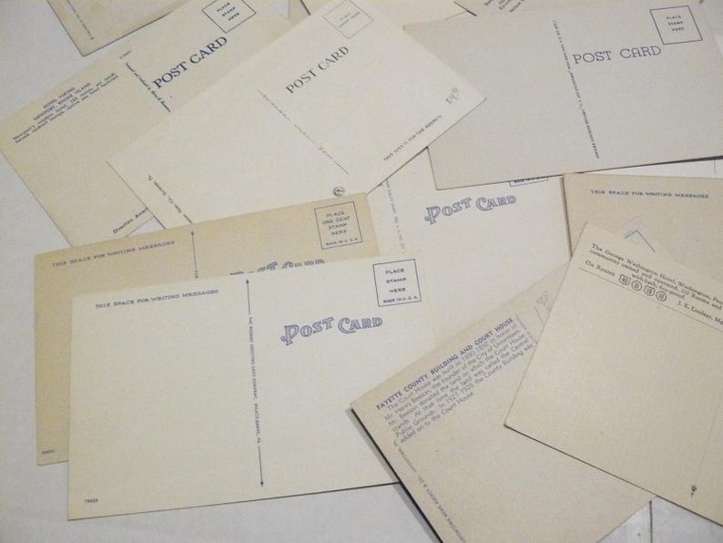 May include: A collection of vintage postcards, with the words "POST CARD" printed on the back. The postcards are cream-colored and feature space for writing messages and placing stamps. Some postcards have text describing buildings and locations.