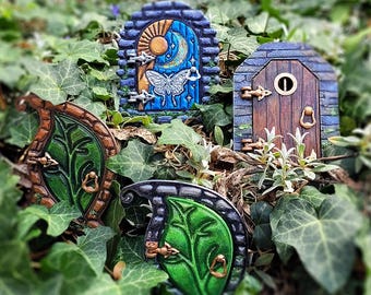 May include: Four miniature fairy doors made of wood and painted with various designs. One door is blue with a moon and stars, another is brown with a knocker, and two are green with leaf designs.
