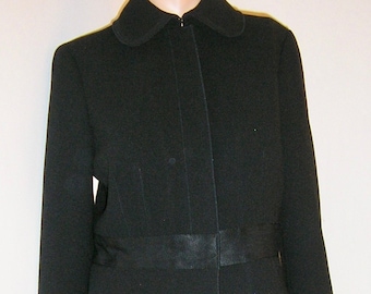 May include: A black suit jacket with a skirt. The jacket has a Peter Pan collar and a single button closure. The skirt is knee-length.