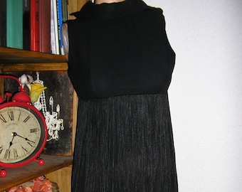 May include: A black sleeveless dress with a fringe hem. The dress has a mock neck and a fitted bodice.