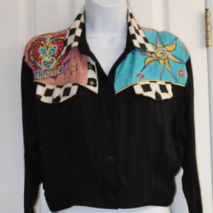 May include: A black button-up shirt with a cropped length. The collar is decorated with a black and white checkered pattern and colorful fabric appliques featuring a heart, a sun, and the word "LOVE".