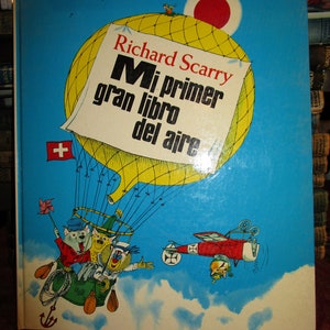 May include: A colorful children's book titled "Richard Scarry Mi primer gran libro del aire" featuring a hot air balloon with animals and a small airplane in the sky.