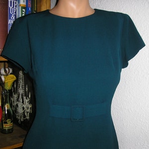 Pode incluir: Um vestido azul-turquesa com manga curta e um cinto com fivela.