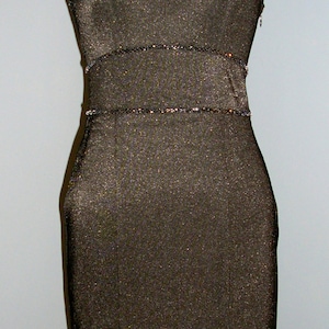 May include: A black sleeveless dress with a sparkly trim around the neckline and waist. The dress has a slit up the front.