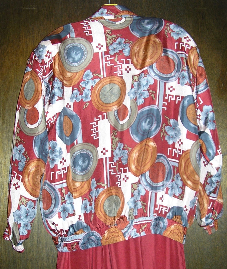 May include: A red, white, and blue patterned jacket with a geometric design. The jacket has a zipper closure and long sleeves.