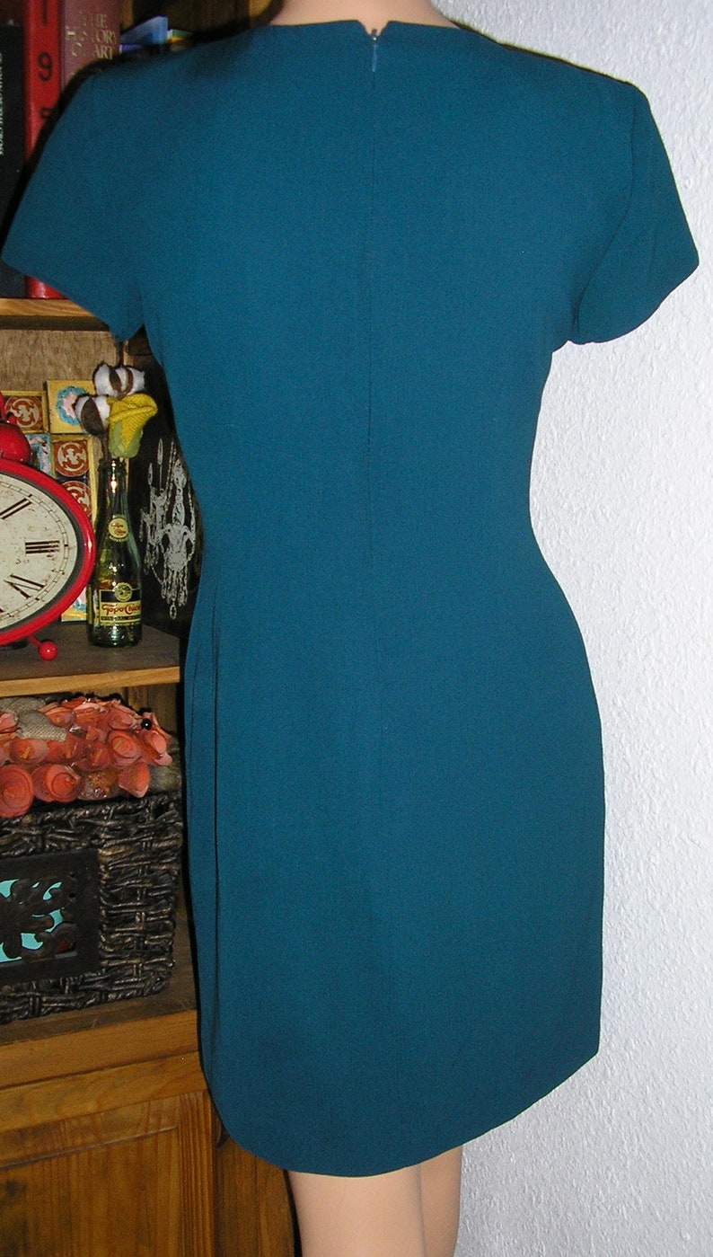Pode incluir: Um vestido azul turquesa de manga curta com z&iacute;per nas costas.