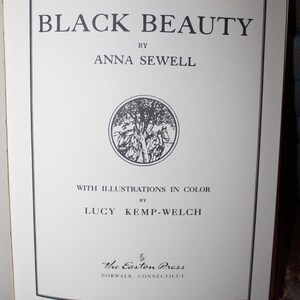 K&ouml;nnte beinhalten: Titelseite des Buches "Black Beauty" von Anna Sewell, mit Illustrationen von Lucy Kemp-Welch. Der Titel ist gro&szlig; geschrieben. Eine runde Illustration von Pferden und B&auml;umen ist enthalten. Ver&ouml;ffentlicht von The Easton Press, Norwalk, Connecticut.