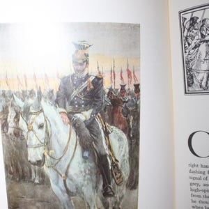K&ouml;nnte beinhalten: Buchillustration zeigt einen Mann in dunkler Uniform auf einem wei&szlig;en Pferd, der Soldaten anf&uuml;hrt. Das Kunstwerk verwendet ged&auml;mpfte Farben, mit roten Fahnen im Hintergrund. Der Titel "The Morning of Balaclava" befindet sich am unteren Bildrand.