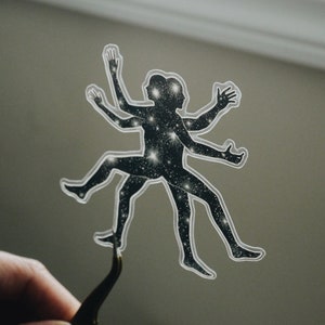 May include: A clear sticker with a silhouette of a person with multiple arms and legs. The silhouette is filled with a pattern of white stars on a black background.