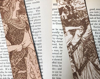 May include: Two vintage bookmarks with illustrations. The first bookmark features a woman in a long dress with intricate patterns. The second bookmark features a woman in a long dress with her hand on her forehead, looking up at the sky. Both bookmarks are printed on cream-colored paper.